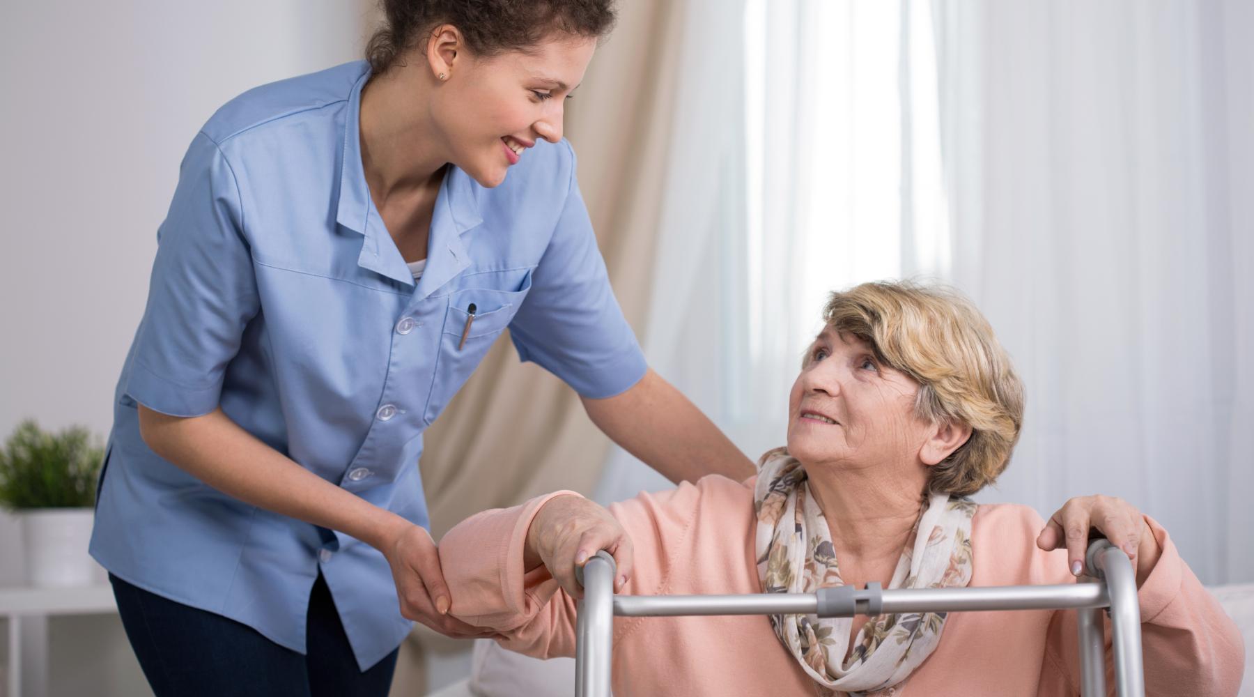 Senior woman using walking frame and supporting nurse